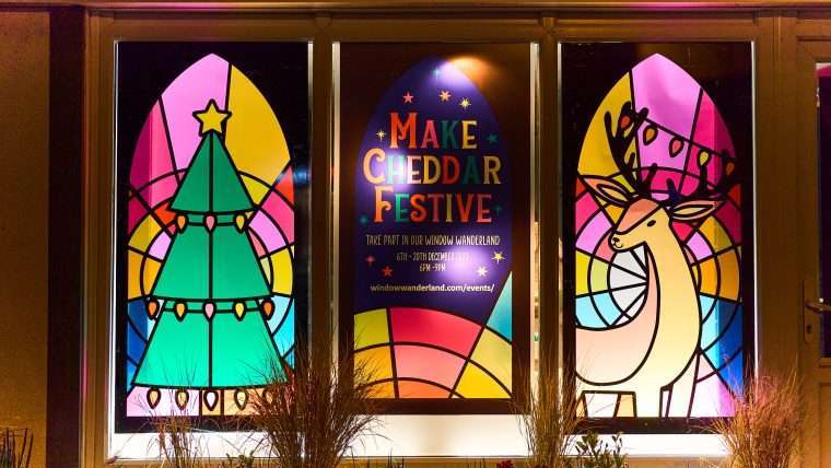 Photo of a window decorated with images of a Christmas tree and Reindeer with the wording 'Make Cheddar Festive'